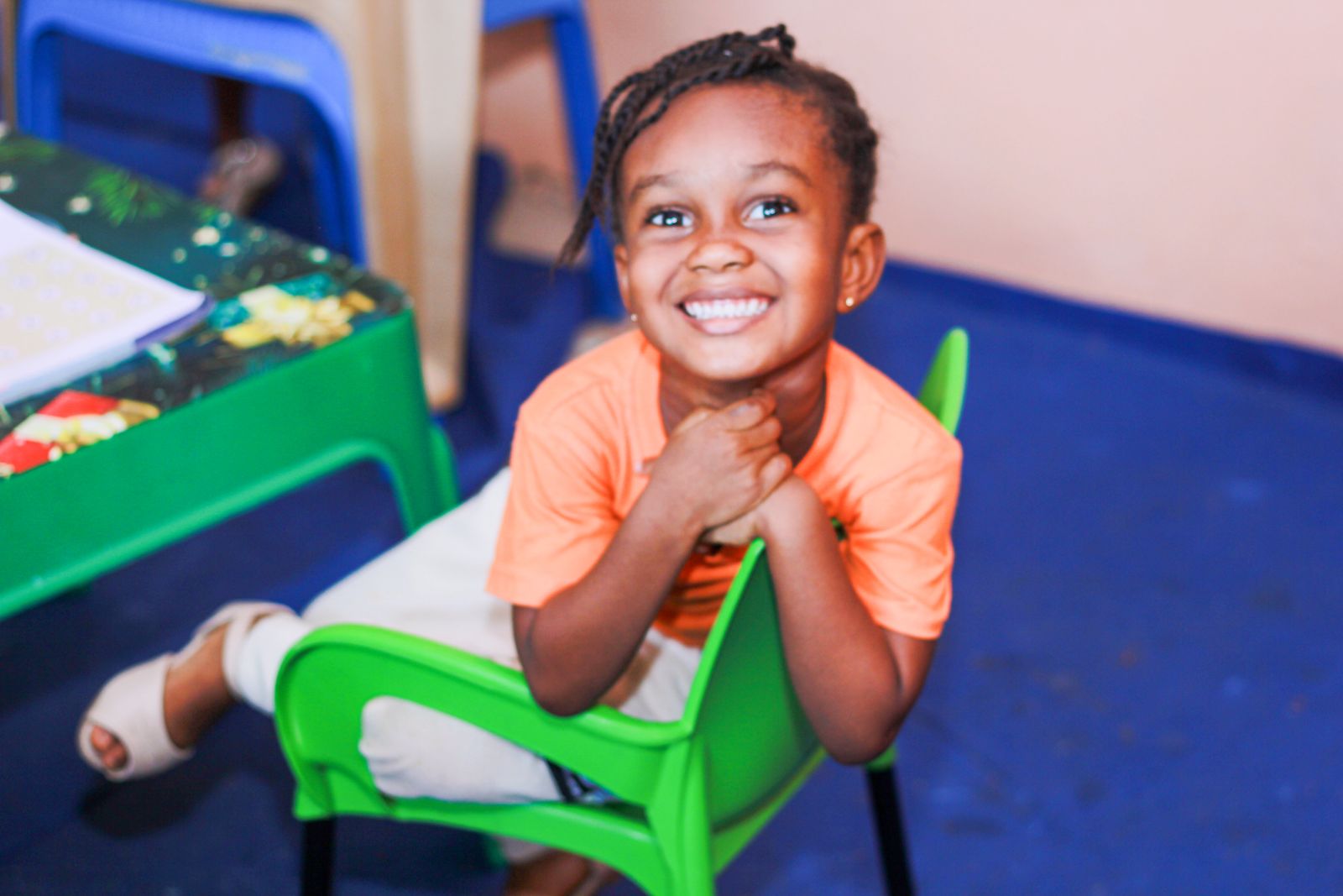 A smiling girl leaning on the back of a green chair